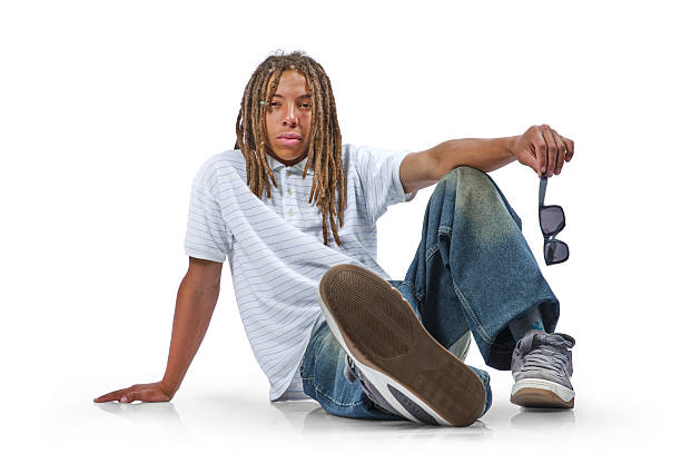 istock Young man with dreadlocks sitting on floor holding sunglasses 2243654034