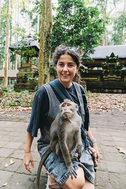 istock Woman smiling with monkey on lap in Ubud Monkey Forest, Bali 2243659435