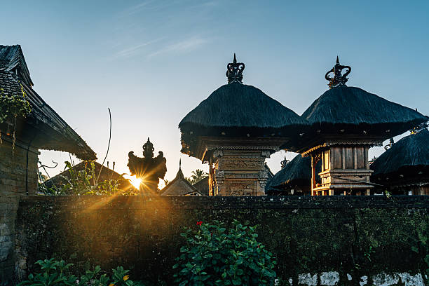Morning sunrays shining through a Balinese temple structure, highlighting intricate traditional architecture and serene tropical surroundings