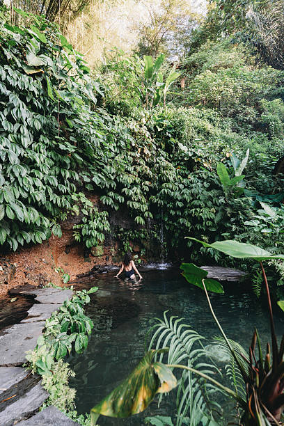 istock Woman enjoying natural tropical pool with waterfall 2243660038