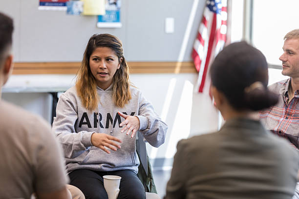 istock Woman in Army sweatshirt leads discussion during a group therapy session indoors. 2243660549