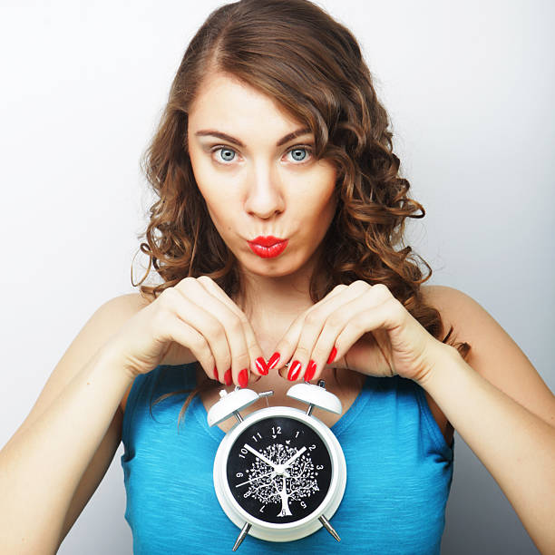 Young happy curly woman with alarmclock