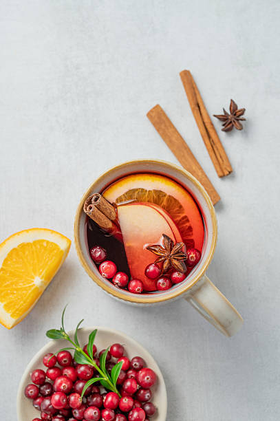 istock A hot cranberry Christmas drink in a mug on a light  background with cinnamon, berries and fruits. 2243664350