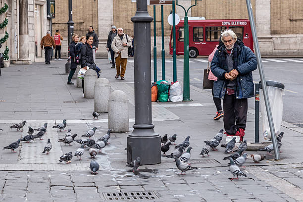 Rome, Italy - December 01, 2019:  An old man feeds the pigeons