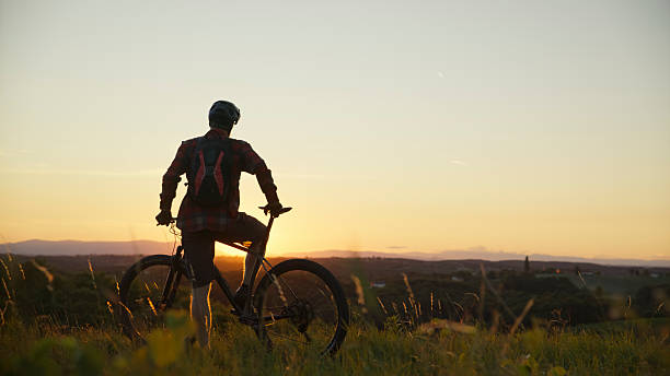istock Contemplative Cyclist Enjoying Tranquil Sunset View From Grassy Hilltop 2243666115