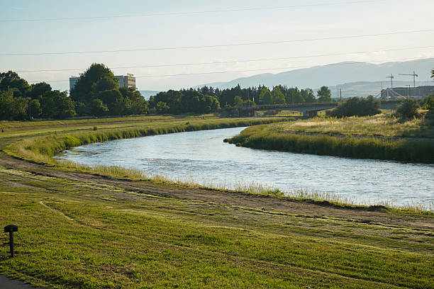 istock Tranquil riverside landscape with lush greenery, rolling hills, and a clear blue sky, perfect for nature and outdoor-themed visuals. 2243666326
