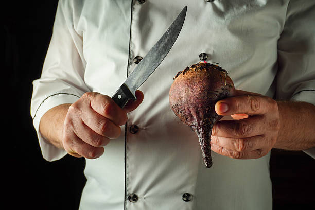 istock A skilled chef holds a fresh beetroot in one hand and a sharp knife in the other. The scene captures the focus and precision required in food preparation, with a dark kitchen background 2243666512