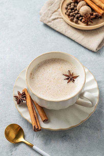 istock Traditional Indian masala chai tea with milk and spices in a white cup on a light blue background with spoon. 2243668730