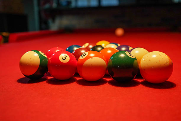 istock Close-up of billiard balls arranged on a red pool table under warm lighting 2243669399