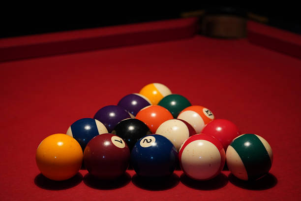 istock Close-up of billiard balls arranged on a red pool table under warm lighting 2243669447