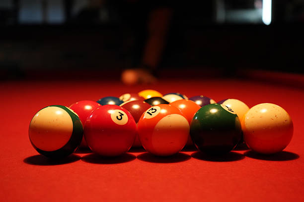 istock Close-up of billiard balls arranged on a red pool table under warm lighting 2243669459