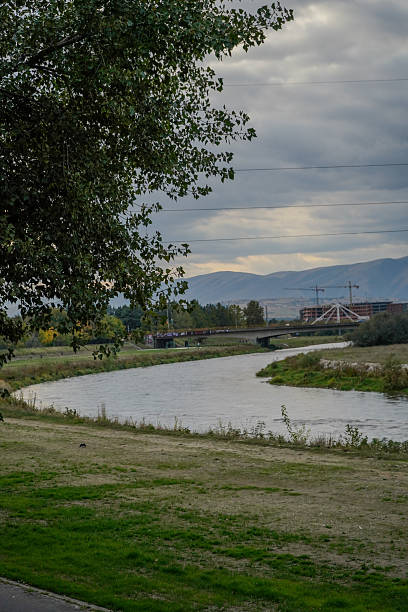 Tranquil riverside landscape with lush greenery, rolling hills, and a clear blue sky, perfect for nature and outdoor-themed visuals.