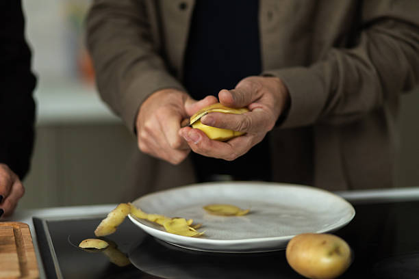 Person peeling potato on a plate in a modern kitchen setting