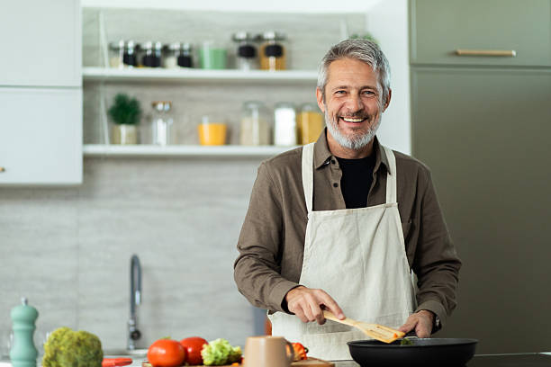 istock Senior man smiling while cooking healthy meal in kitchen 2243673397