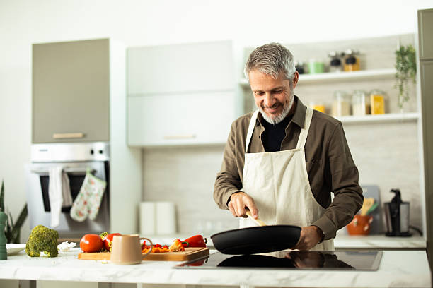 istock Mature adult man cooking vegetables in modern kitchen 2243673475