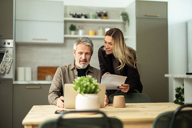 istock Mature couple planning home finances using laptop at kitchen table 2243673741