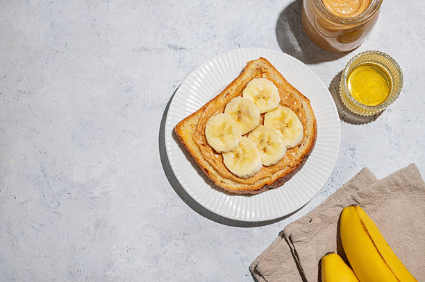 istock Peanut butter toast with banana on a plate on a light background  with spread, fruit, honey 2243674576