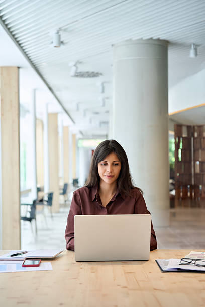 istock Focused young middle eastern business woman specialist working focused on laptop computer. Middle aged latin hispanic investor, bank worker using pc for analysing, network at desk in office. Vertical 2243679740