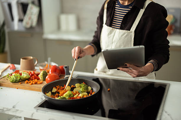 istock Woman cooking fresh vegetables using digital tablet for recipe 2243679859
