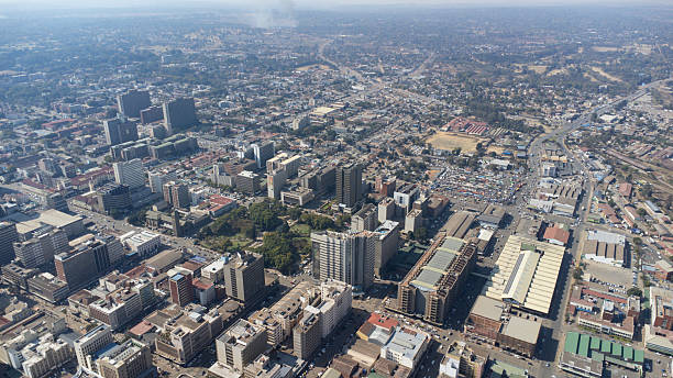 Expansive cityscape with buildings, green spaces, and a distant horizon under blue sky