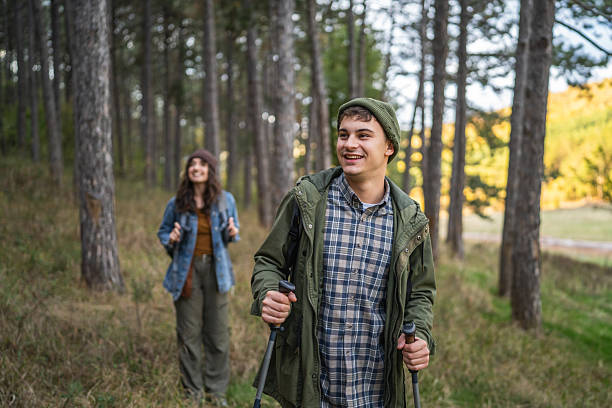istock Young couple smiling, hiking in forest using trekking poles 2243681673
