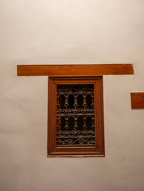 istock Traditional Moroccan Architecture Featuring a Decorative Wooden Window Frame and Intricate Wrought Iron Security Bars on a Plain Wall 2243683743