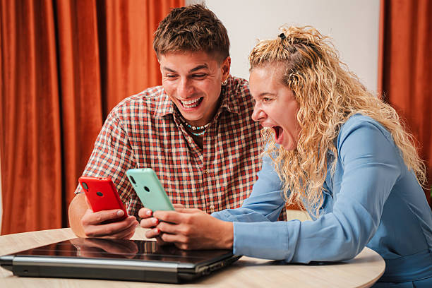 istock Two friends share a joyful moment while engaging with their smartphones in a fun and lively manner 2243686704