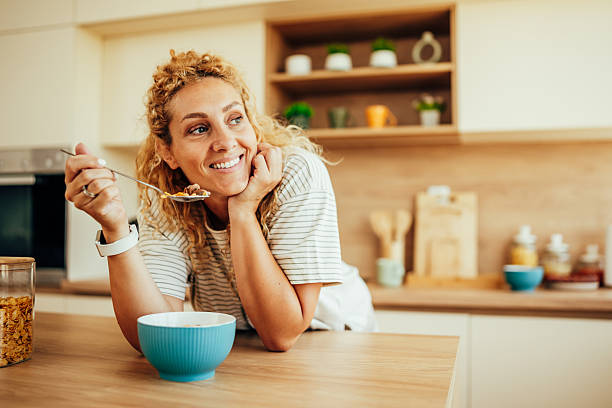 istock Happy woman eating breakfast cereal in kitchen 2243687480