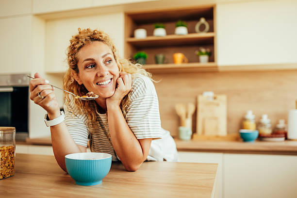 istock Smiling woman eating healthy breakfast cereal in kitchen 2243687490