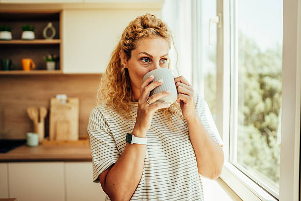 istock Woman enjoying morning coffee in kitchen by window 2243687533
