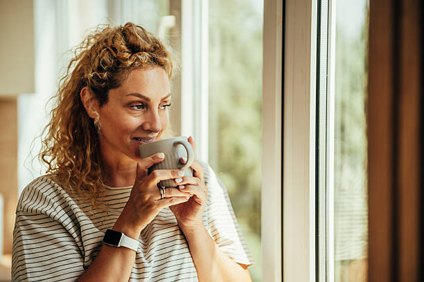 istock Woman drinking coffee looking out window in morning 2243687538