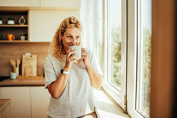 istock Woman enjoying morning coffee in kitchen looking out window 2243687541