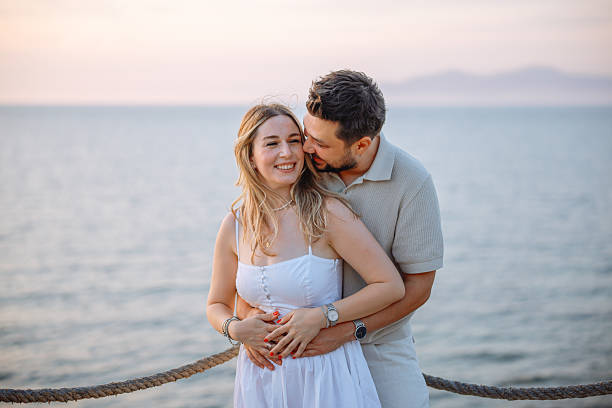 istock Young couple laughing and embracing on the beach 2243688381
