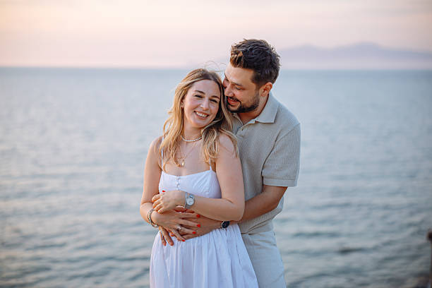 istock Young couple laughing and embracing on the beach 2243688420