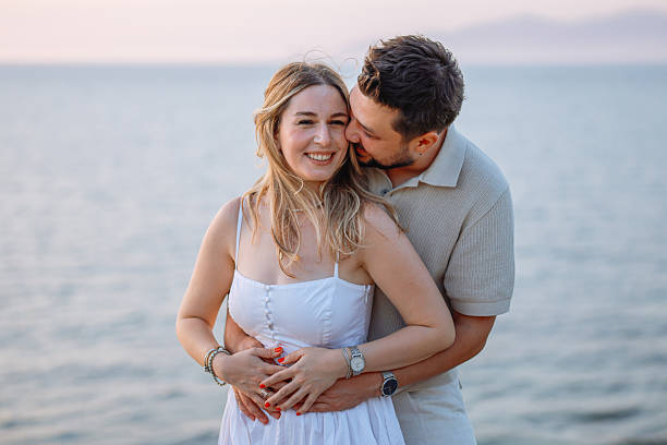 istock Young couple laughing and embracing on the beach 2243688691