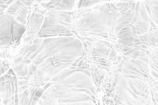istock White water with ripples on the surface. Defocus blurred transparent white colored clear calm water surface texture with splashes and bubbles. Water waves with shining pattern texture background. 2243689403