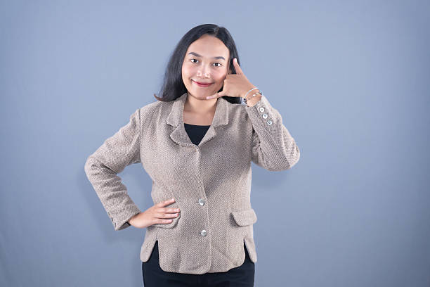 istock A smiling young woman in a blazer making a call me gesture with her left hand. 2243693655