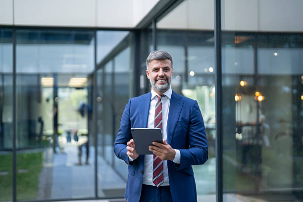 istock Smiling businessman holding tablet in modern office building 2243696457