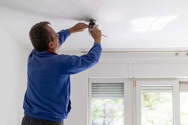 istock Ceiling light installation. Electrician installing, adjusting electrical lamp during home renovation. Worker on ladder fixing overhead lightbulb. 2243697729