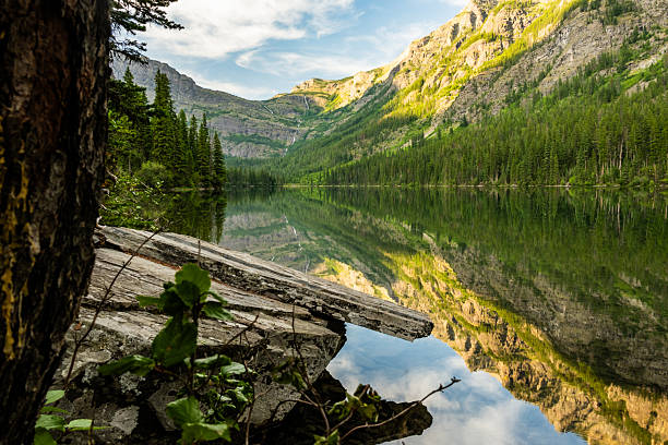 Rock Shelf Hangs Over Glassy Grace Lake In Glacier National Park
