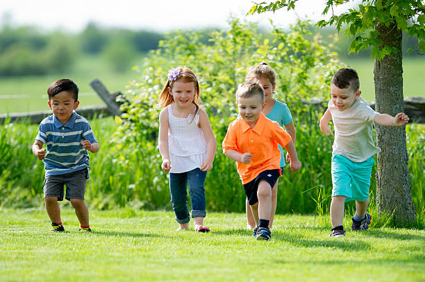 istock Five Diverse Children Run Together Outdoors in a Lush Green Park Setting 2243701288