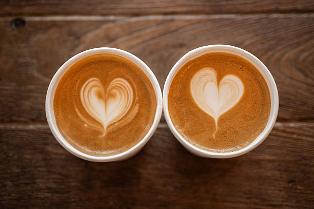 Couple cups of cappuccino coffee on wooden table.