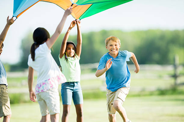 istock Diverse Group Of Kids Playing Outdoors With A Kite In A Sunlit Park 2243703869