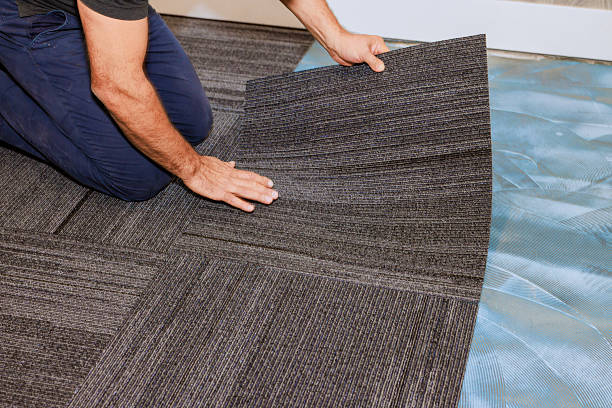 istock Installer lays down modern carpet tiles in contemporary office space 2243707673