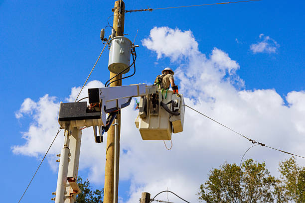 istock Utility worker performs maintenance on power lines during works day with bright blue skies and fluffy clouds 2243707788