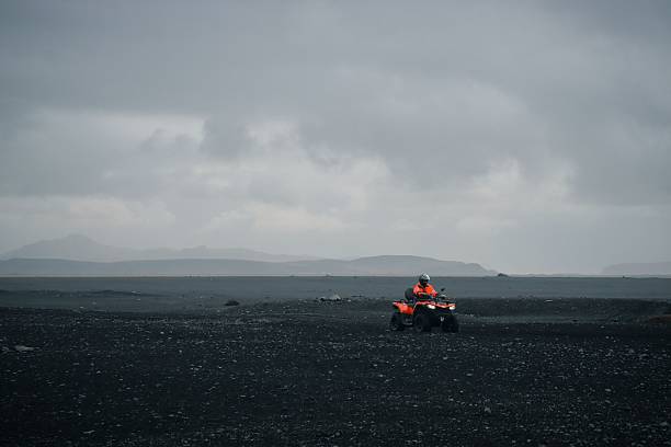 Reykjavik, Iceland – October 23, 2024: Man in red jacket riding an ATV on Iceland's black sand beach