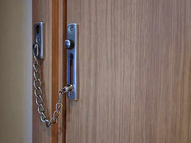 Balikpapan-indonesia 12/18/2024 Close-up of an open, silver metal door chain lock and bolt mechanism on a wooden interior door, symbolizing security and privacy in a home or hotel.