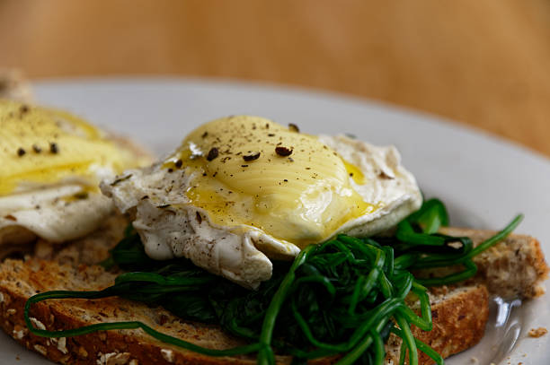 Poached eggs on a bed of spinach, on full grain toast. They have butter melting on top of them.
