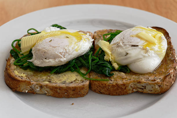 Poached eggs on a bed of spinach, on full grain toast. They have butter melting on top of them.