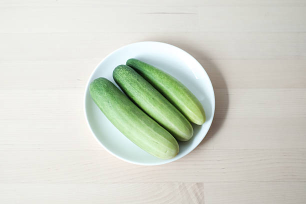 Fresh cucumber in white plate on the wooden table.